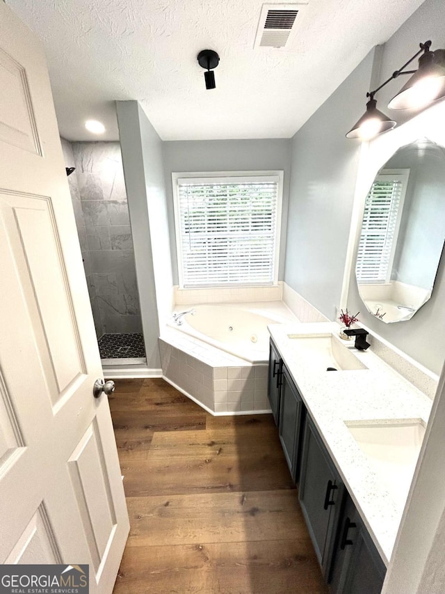 bathroom featuring vanity, wood-type flooring, shower with separate bathtub, and a textured ceiling