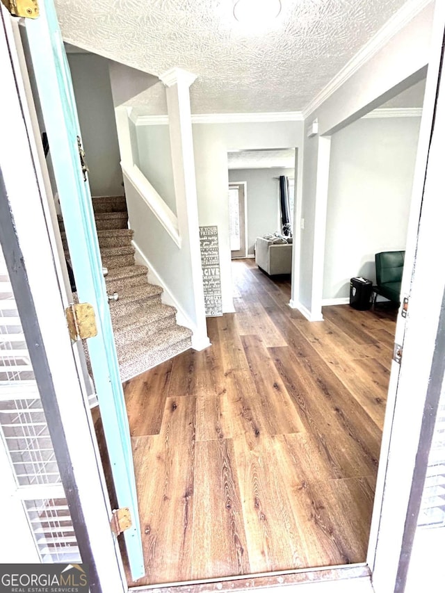 entryway featuring crown molding, wood-type flooring, and a textured ceiling