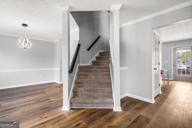 stairway with crown molding, baseboards, wood-type flooring, and a textured ceiling