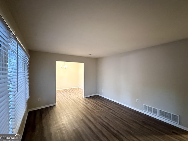 empty room with hardwood / wood-style floors and a notable chandelier