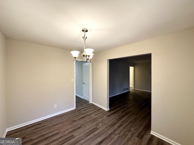 unfurnished room with dark wood-type flooring and a notable chandelier