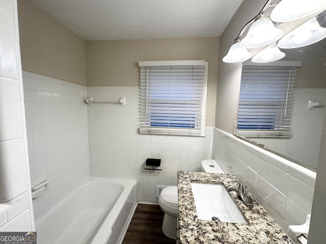 bathroom with toilet, wood-type flooring, tile walls, vanity, and a bath