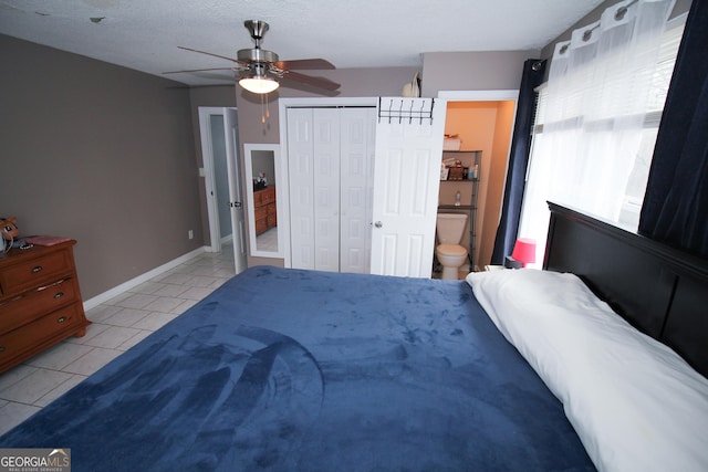 bedroom featuring light tile patterned floors, ensuite bath, ceiling fan, a textured ceiling, and a closet