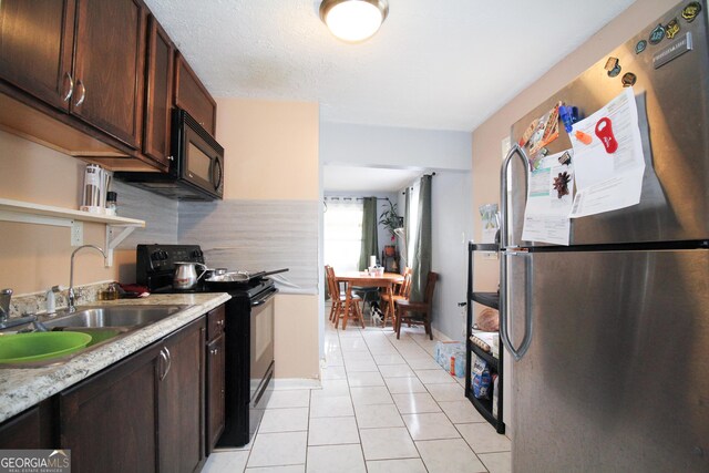 kitchen featuring light tile patterned floors, dark brown cabinetry, sink, and black appliances