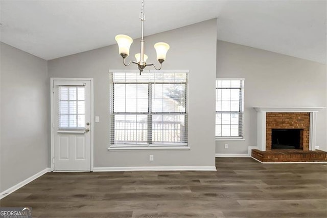 interior space with lofted ceiling, dark hardwood / wood-style floors, a chandelier, and a brick fireplace