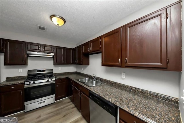 kitchen with sink, appliances with stainless steel finishes, dark brown cabinetry, wood-type flooring, and a textured ceiling