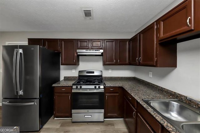 kitchen with stainless steel appliances, sink, a textured ceiling, and light hardwood / wood-style flooring