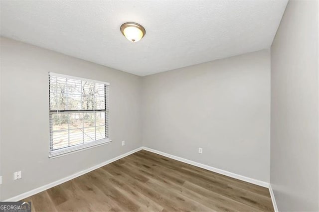 unfurnished room featuring dark hardwood / wood-style flooring and a textured ceiling