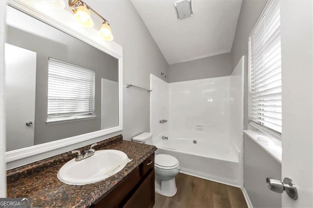 full bathroom featuring a healthy amount of sunlight, washtub / shower combination, wood-type flooring, and toilet