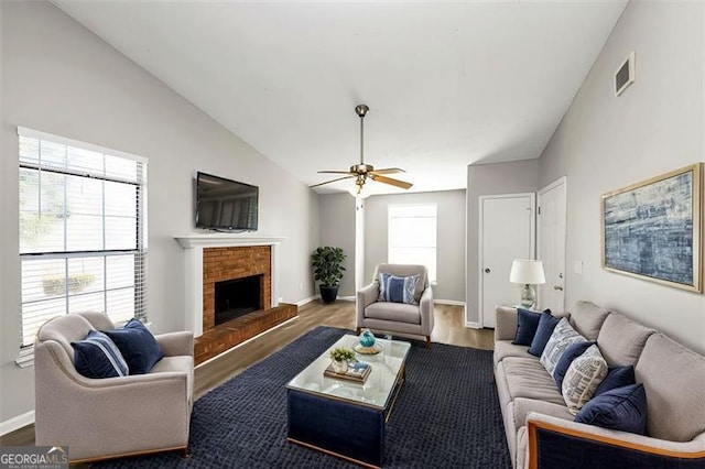 living room featuring a brick fireplace, dark wood-type flooring, ceiling fan, and vaulted ceiling