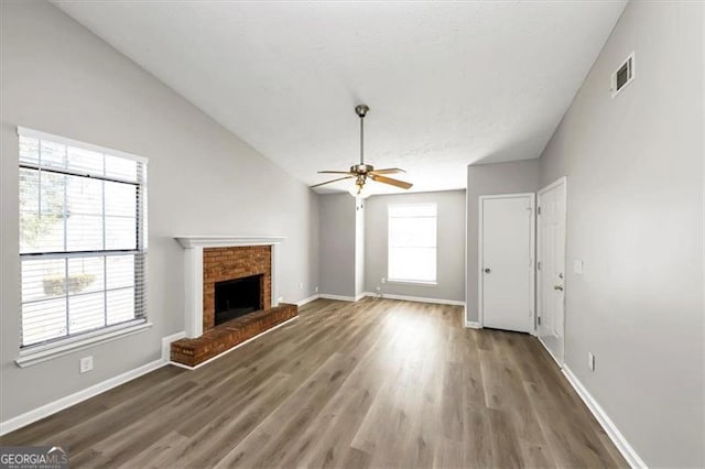 unfurnished living room with ceiling fan, lofted ceiling, dark hardwood / wood-style floors, and a fireplace