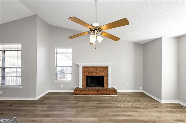 unfurnished living room featuring ceiling fan, lofted ceiling, dark wood-type flooring, and a fireplace