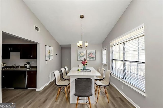 dining room featuring sink, vaulted ceiling, dark hardwood / wood-style floors, and a chandelier