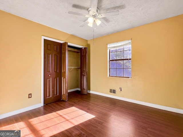 unfurnished bedroom with hardwood / wood-style flooring, a textured ceiling, ceiling fan, and a closet