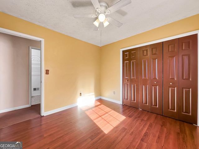 unfurnished bedroom with ceiling fan, wood-type flooring, a closet, and a textured ceiling