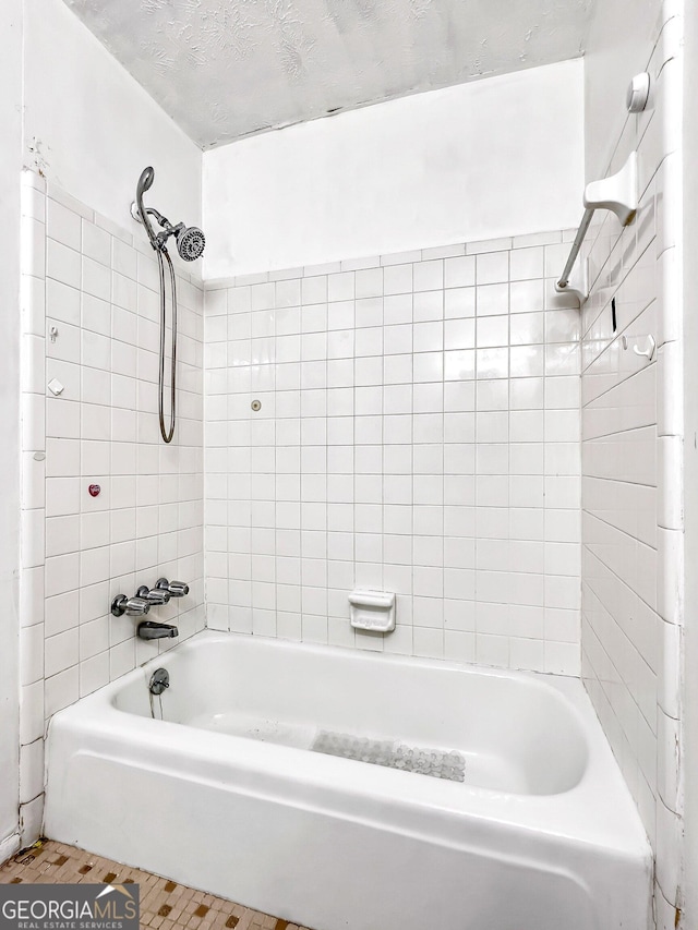 bathroom with tiled shower / bath combo, tile patterned floors, and a textured ceiling