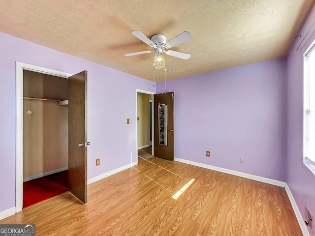 unfurnished bedroom featuring a textured ceiling, light hardwood / wood-style flooring, a closet, and ceiling fan