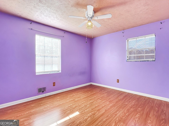 empty room featuring ceiling fan, light hardwood / wood-style flooring, and a textured ceiling