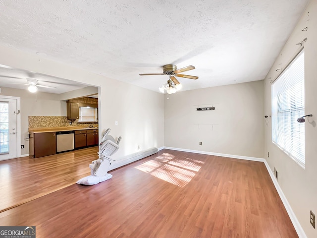 unfurnished living room with ceiling fan, hardwood / wood-style floors, and a textured ceiling