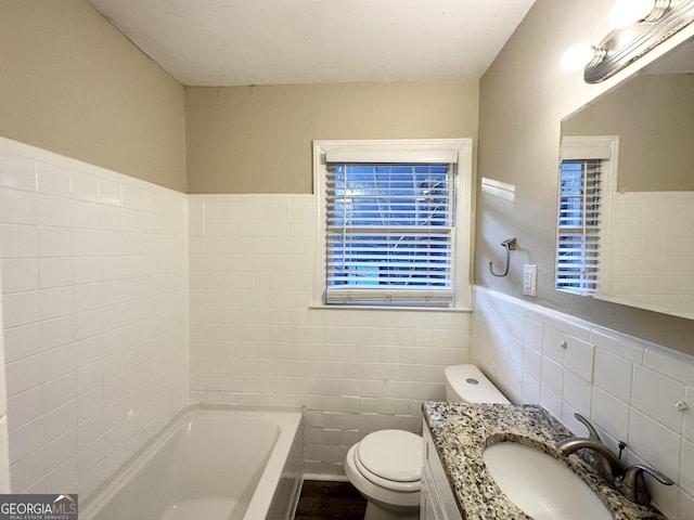 bathroom with tile walls, a bath, vanity, and toilet