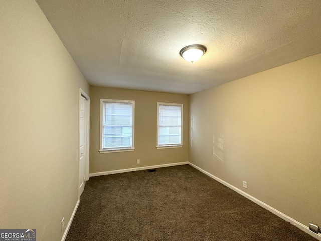 carpeted empty room featuring a textured ceiling