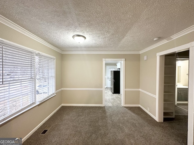 carpeted spare room featuring crown molding and a textured ceiling