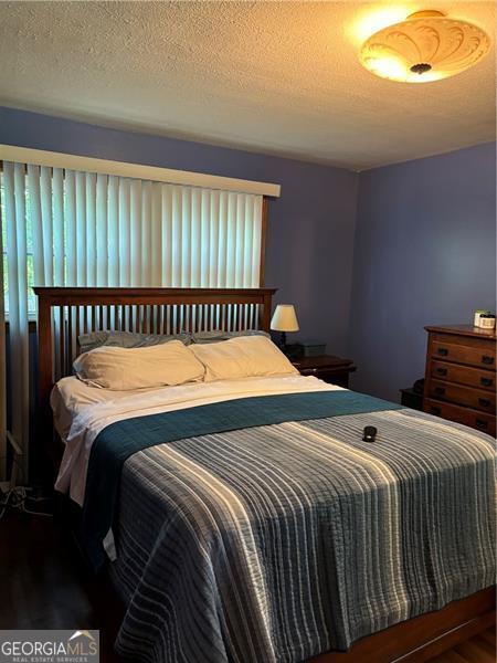 bedroom featuring hardwood / wood-style flooring and a textured ceiling