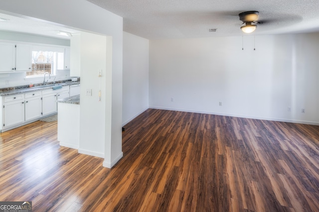 empty room with dark hardwood / wood-style flooring, sink, a textured ceiling, and ceiling fan