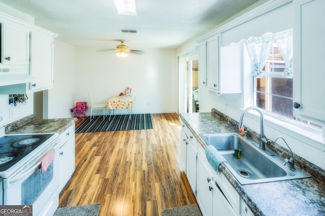 kitchen with white electric range oven, sink, wood-type flooring, a textured ceiling, and white cabinets