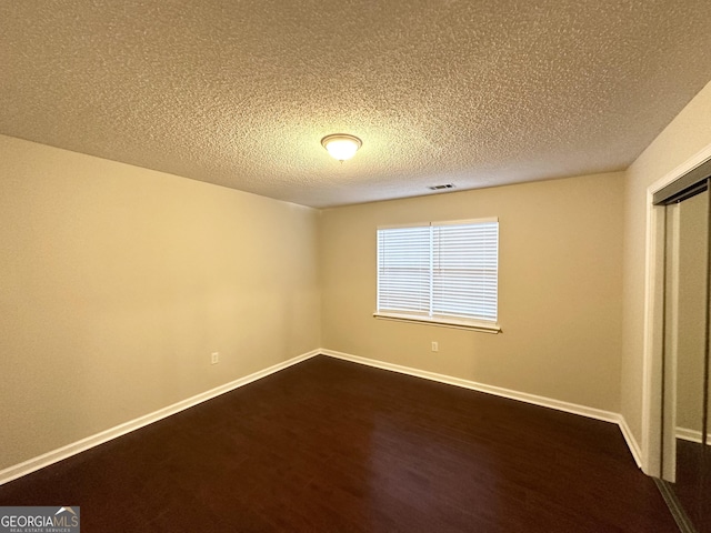 unfurnished bedroom with dark wood-type flooring and a textured ceiling