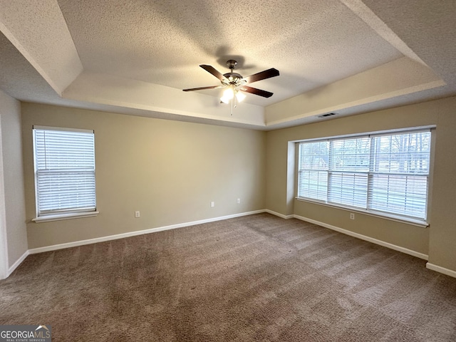 carpeted empty room with ceiling fan, a tray ceiling, and a textured ceiling