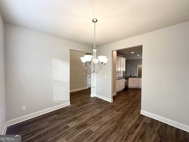 unfurnished dining area with sink, a notable chandelier, and dark hardwood / wood-style flooring