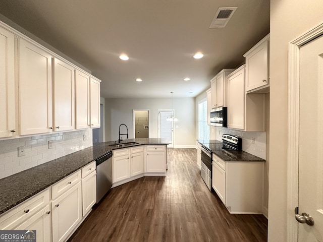 kitchen featuring sink, dark wood-type flooring, appliances with stainless steel finishes, hanging light fixtures, and kitchen peninsula