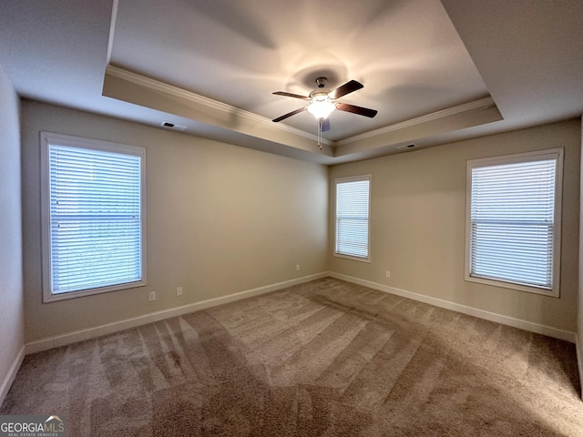 carpeted empty room with a raised ceiling, crown molding, and ceiling fan