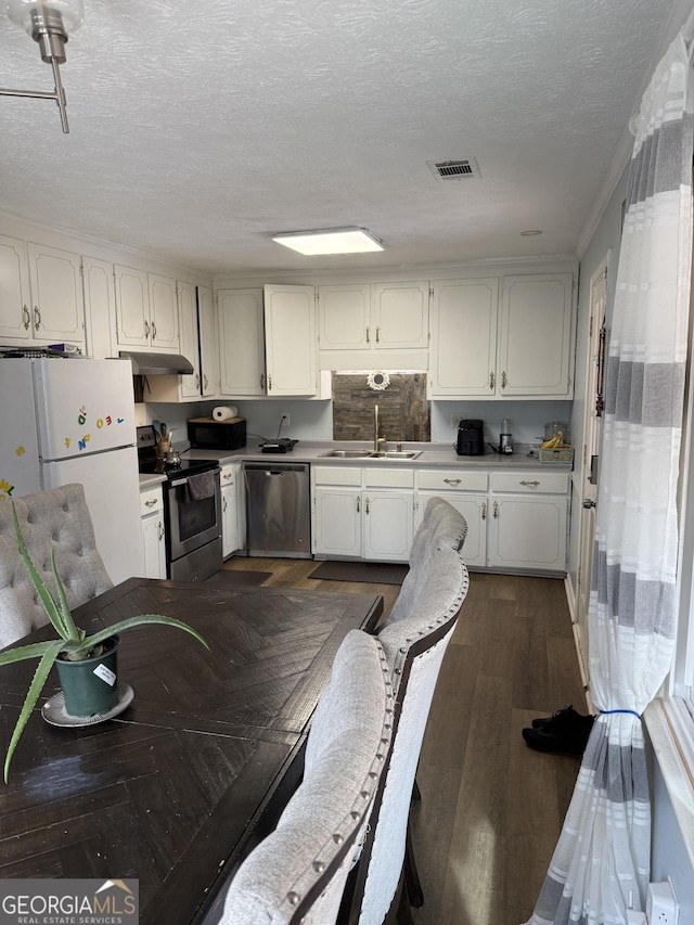 2615 Leeshire Ct, Tucker, GA 30084 - kitchen with stainless steel appliances, a sink, under cabinet range hood, white cabinetry, and a textured ceiling