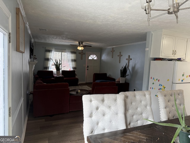 interior space featuring white cabinetry, wood-type flooring, a textured ceiling, white refrigerator, and ornamental molding