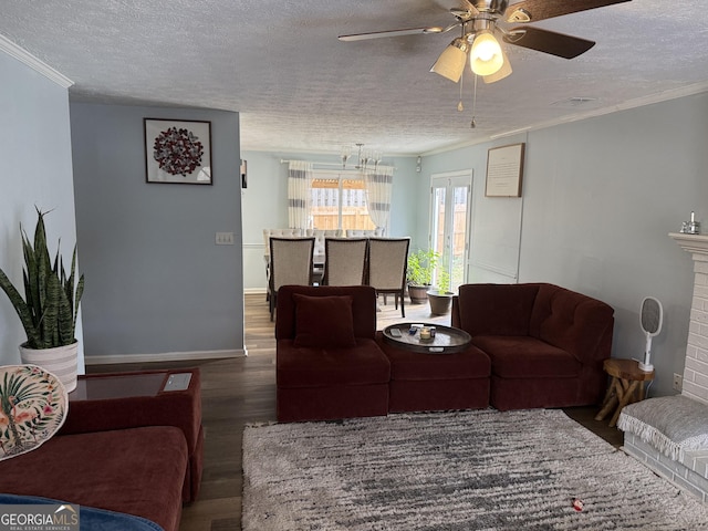 living room with dark wood-type flooring, ceiling fan, ornamental molding, a textured ceiling, and a brick fireplace