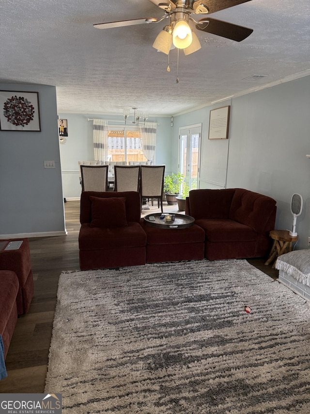 living room featuring ceiling fan, ornamental molding, dark hardwood / wood-style floors, and a textured ceiling