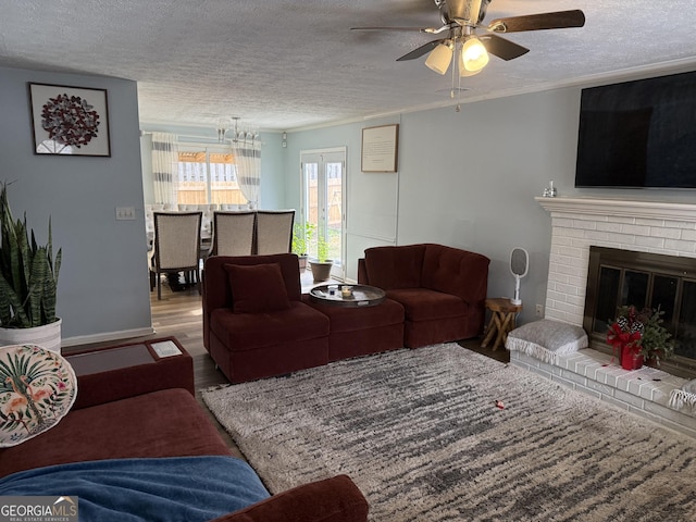 living room featuring ceiling fan, a brick fireplace, hardwood / wood-style floors, and a textured ceiling