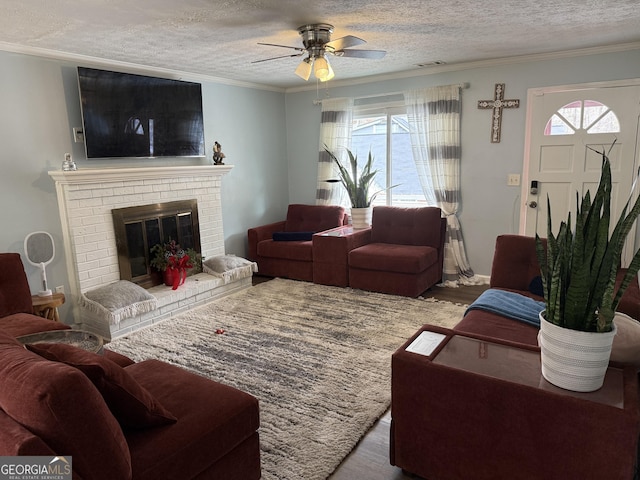 living room with a brick fireplace, light wood-type flooring, a wealth of natural light, and a textured ceiling