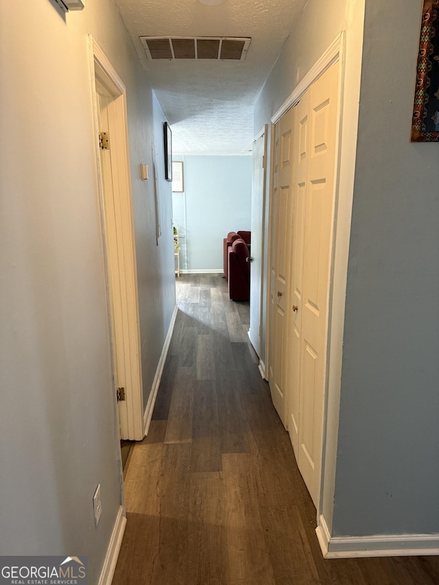 hallway featuring dark hardwood / wood-style flooring and a textured ceiling