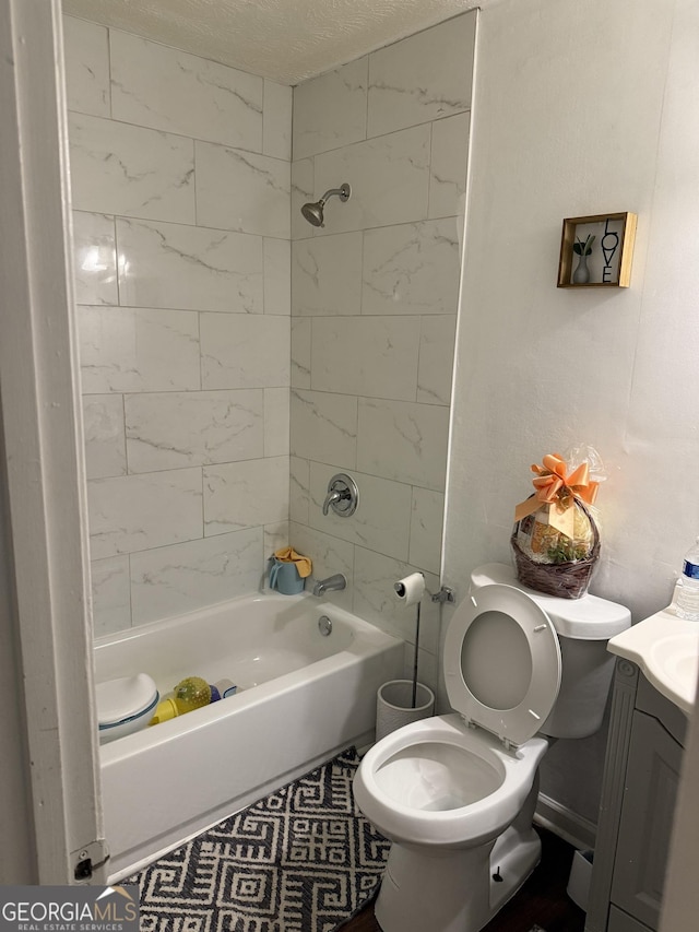 full bathroom featuring tiled shower / bath, vanity, tile patterned floors, and toilet