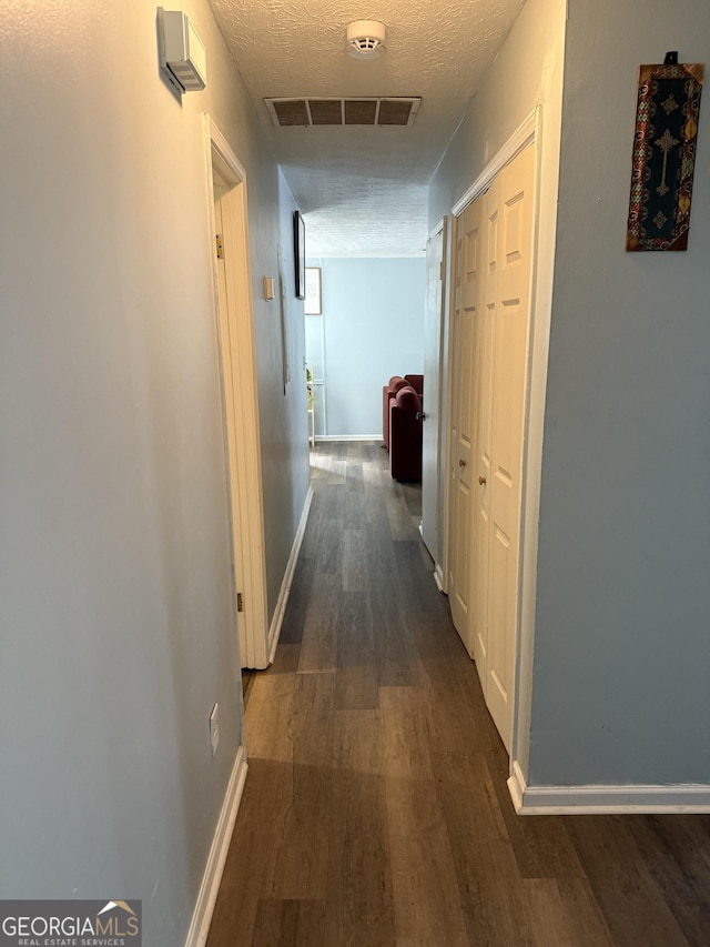 hall with dark wood-type flooring and a textured ceiling