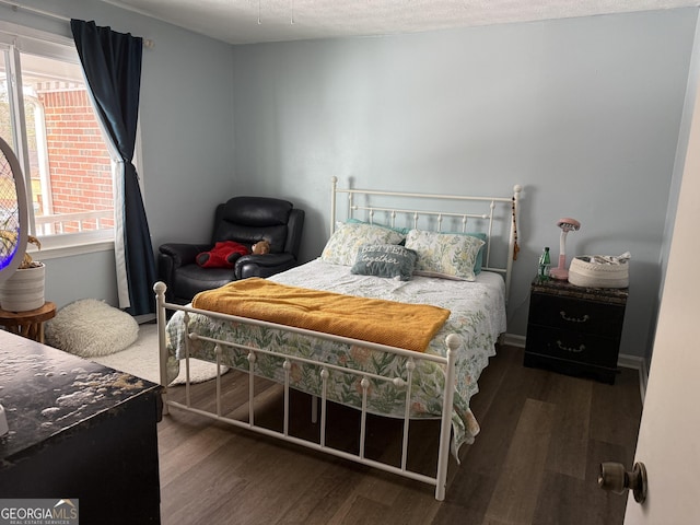 bedroom featuring multiple windows, dark hardwood / wood-style flooring, and a textured ceiling