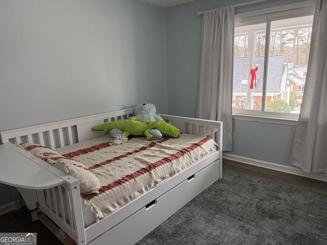 bedroom with multiple windows and dark hardwood / wood-style floors