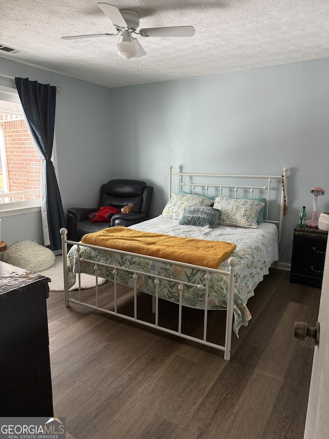 bedroom featuring dark hardwood / wood-style flooring, a textured ceiling, and ceiling fan