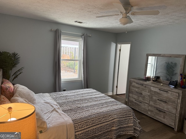 bedroom with dark hardwood / wood-style flooring, a textured ceiling, and ceiling fan