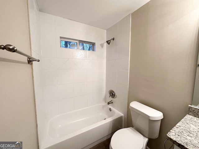 full bathroom with tiled shower / bath, vanity, and toilet