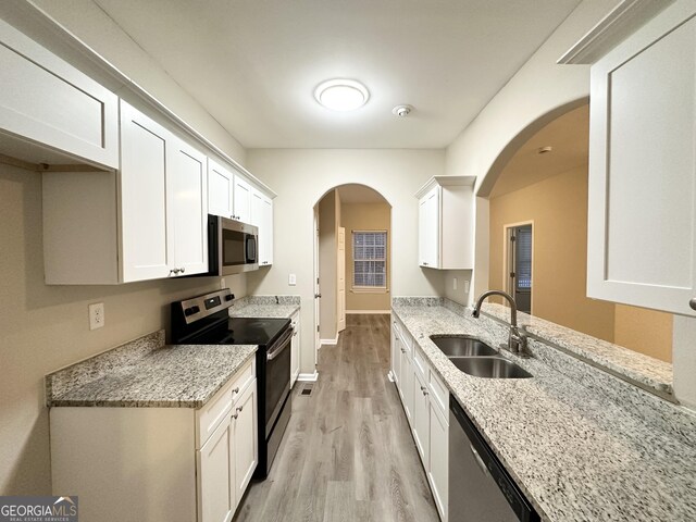 kitchen featuring white cabinetry, appliances with stainless steel finishes, sink, and light stone counters