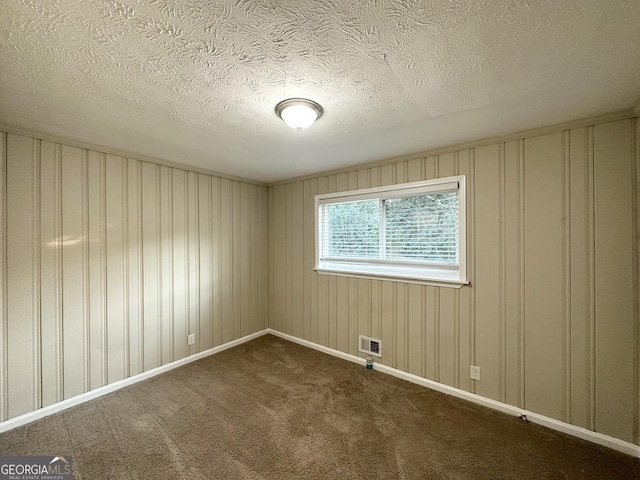 spare room with dark carpet and a textured ceiling